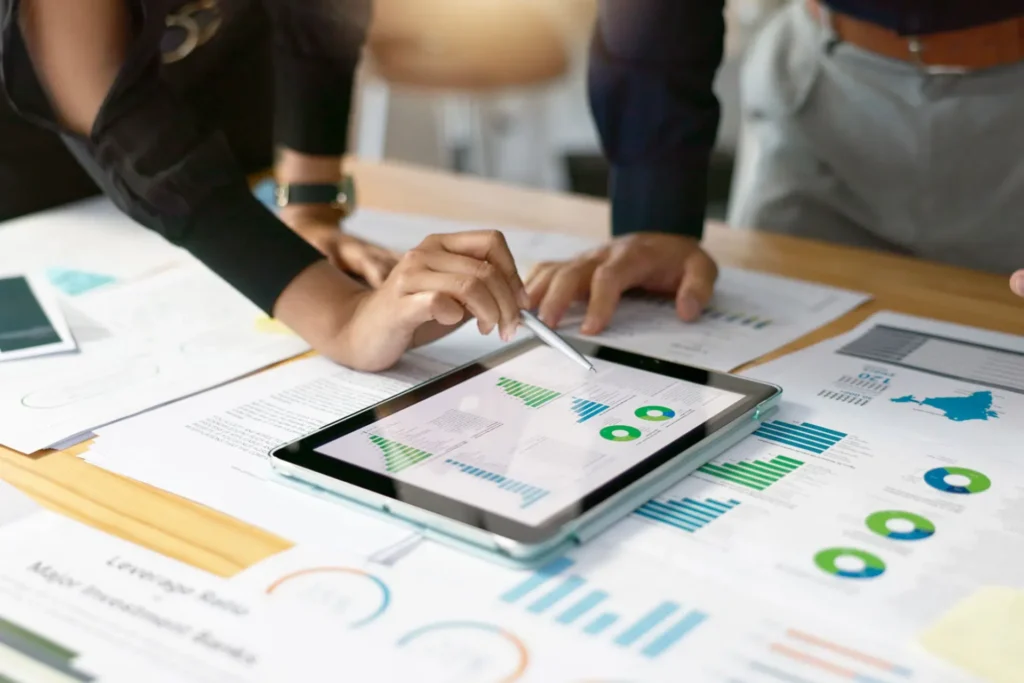 Business professionals analyzing graphs and charts on a tablet, focusing on actionable metrics through technology