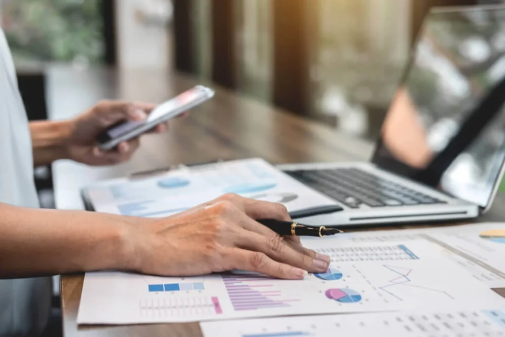 Businesswoman with a laptop and pen, taking notes on cash flow pressures faced by medical practices
