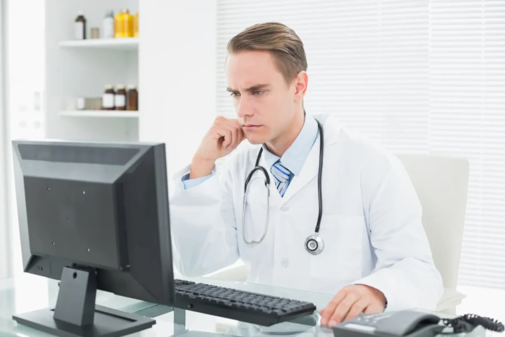 Doctor at his desk with a computer, highlighting the silent threat of medical billing errors in healthcare practices