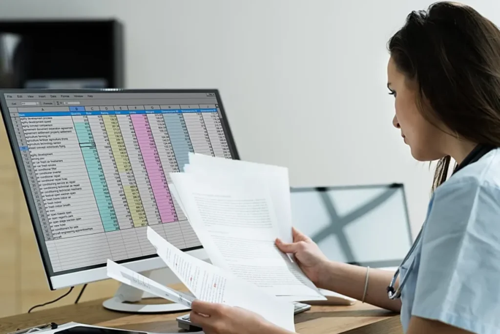 Woman in a blue shirt focuses on a computer screen, highlighting outsourced medical billing for faster reimbursements